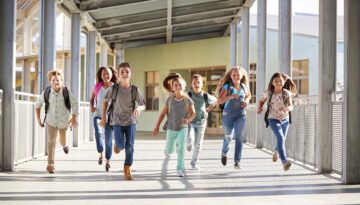 School kids running in elementary school corridor, close up